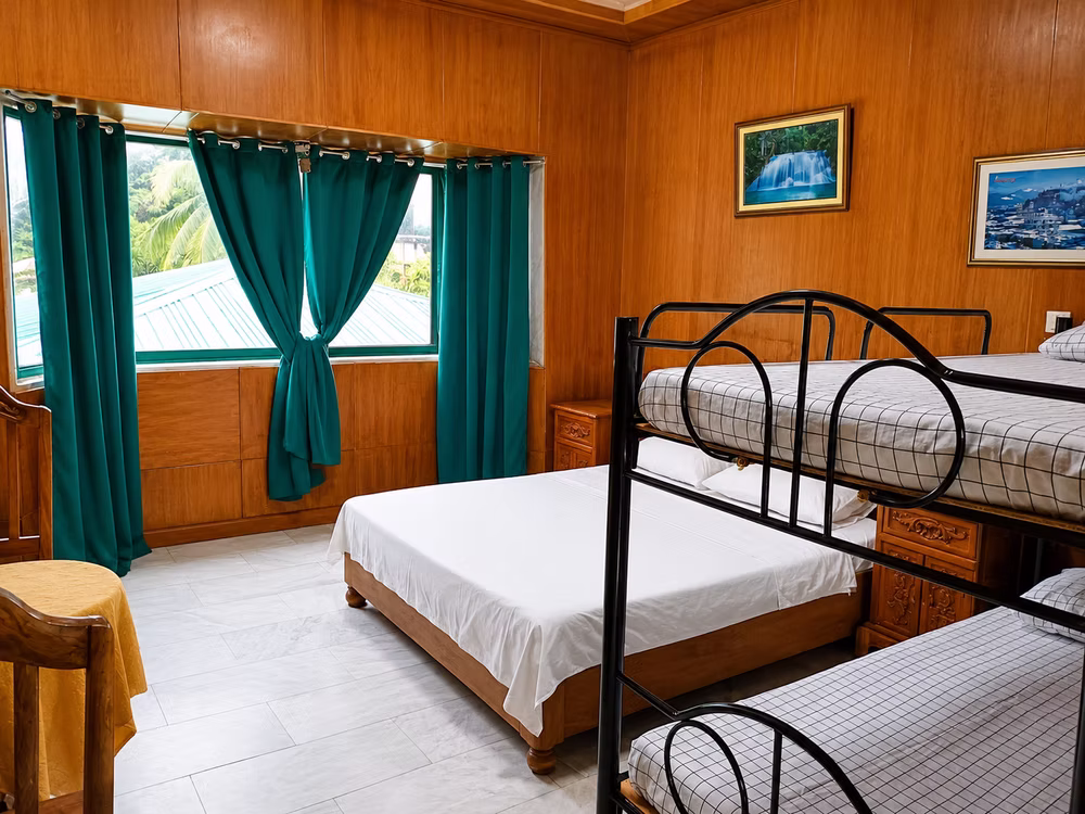 Guest room with a double bed, bunk beds and green curtains