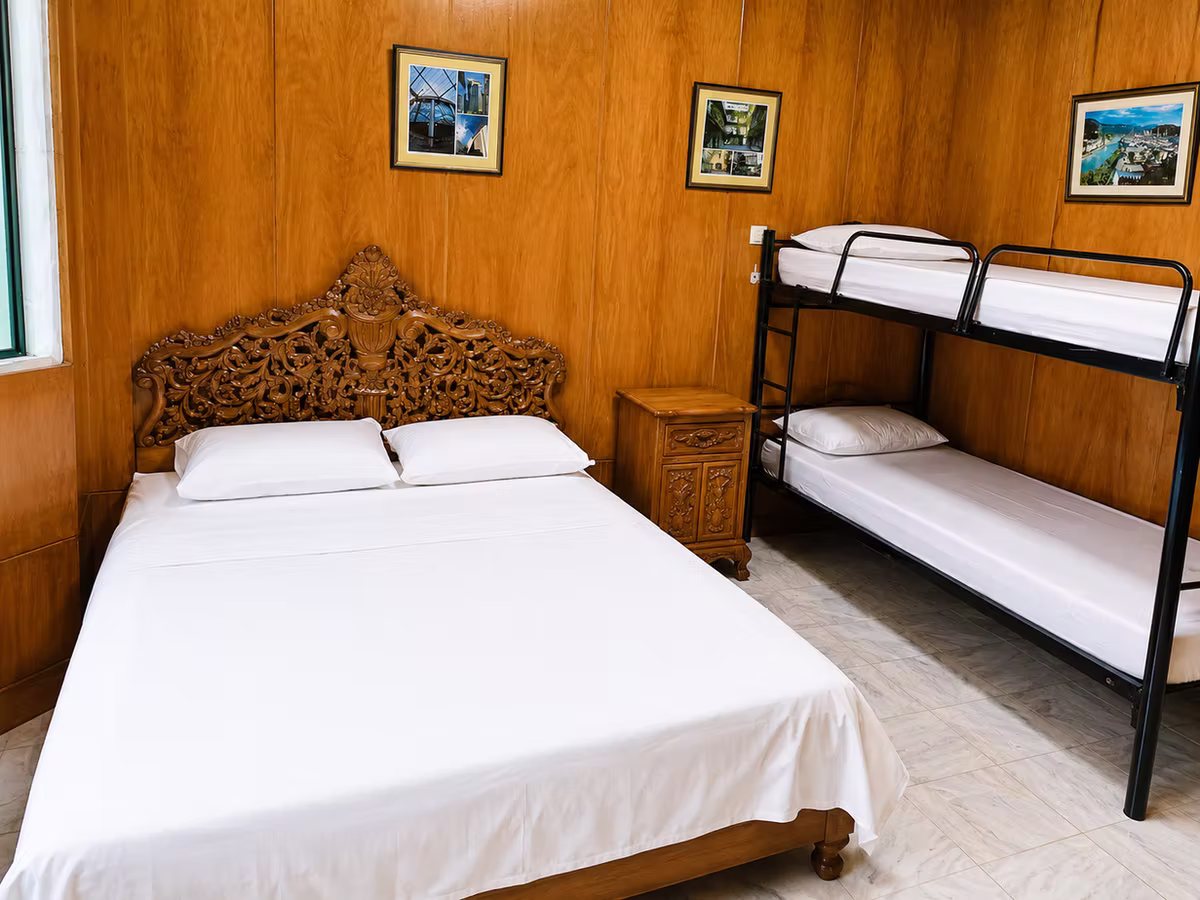 A warm wood-lined guest room with a double bed and bunk beds